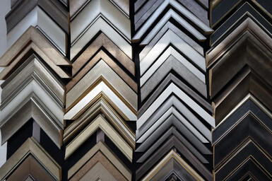 Close-up photograph of picture frame samples in many different colours and finishes, inside a picture framing shop.