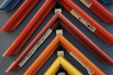 Close-up photograph of picture frame samples in many different colours and finishes, inside a picture framing shop.