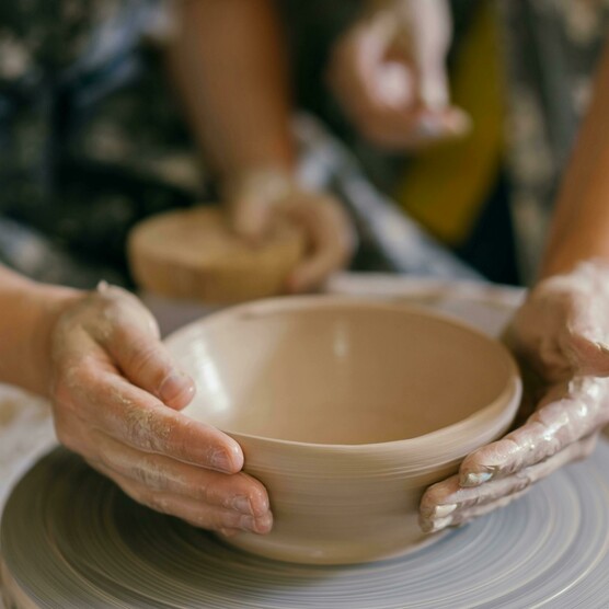 Close-up photo of someone throwing a bowl on a potters wheel