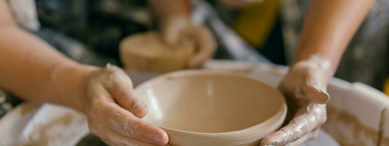 Close-up photo of someone throwing a bowl on a potters wheel