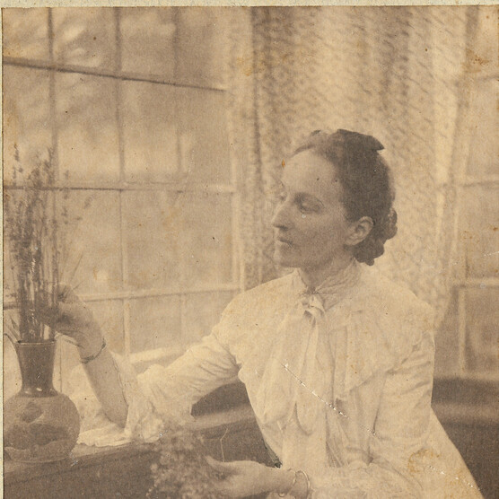 Mary Watts sitting down and tending to a plant on a window sill