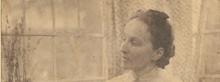 Mary Watts sitting down and tending to a plant on a window sill