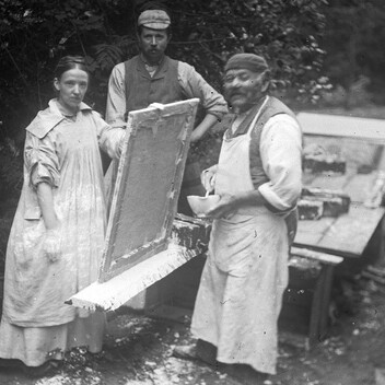 Archive black and white photo of two men and a women looking to camera
