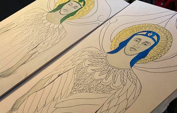 Drawings of two Compton angels halfway through being painted, only their faces and halos have been coloured so far