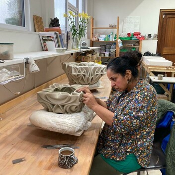 Halima sat at her workbench concentrating on carving a vessel placed on a pillow