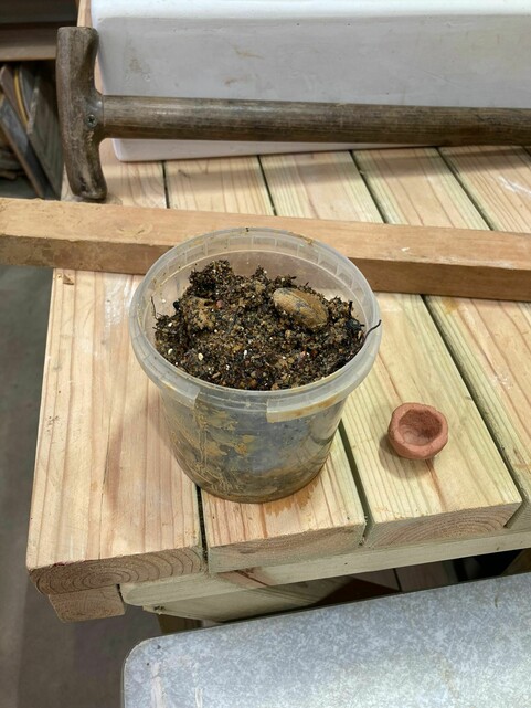 A tub of freshly dug Compton clay next to a small pot made out of the same clay after refined and fired