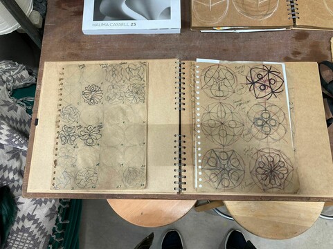 A closeup of one of Halima's sketchbooks, the brown paper filled with geometric design done in pen and ordered in neat rows