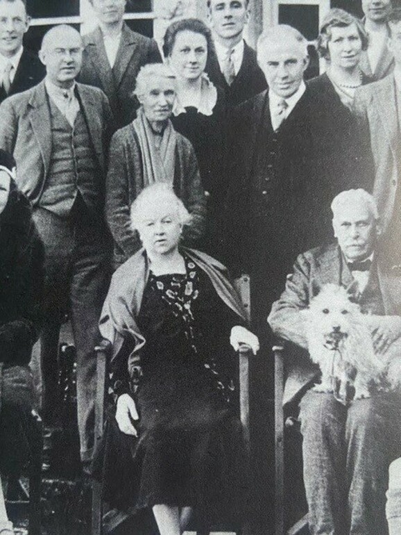 a black and white photograph of a group of people standing and sitting next to each other