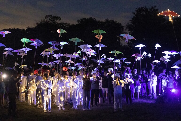 A group of people dressed in white holding illuminated decorations