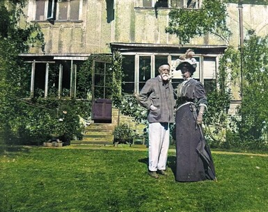 A colour photograph of George and Mary Watts stood outside Limnerslease on the lawn