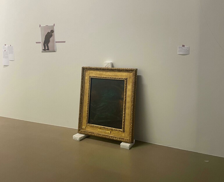 An oil painting in a gold frame sits on foam blocks in a white museum gallery