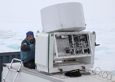Photo of a man in the North Pole investigating a large white radar machine