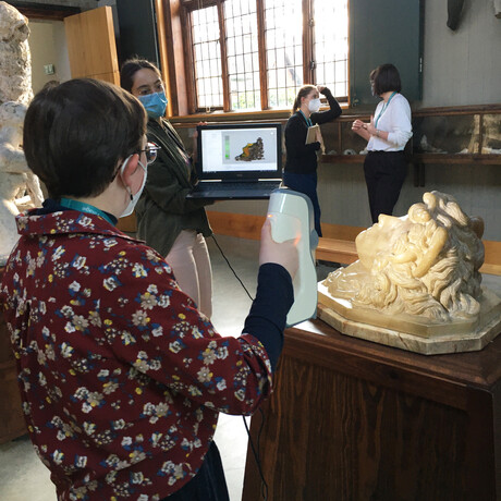 Collections Assistant holds up the 3D scanner to the alabaster medusa sculpture