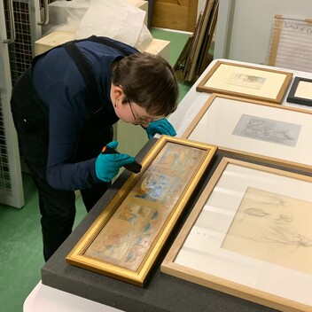 A woman checking pictures frames with a torch