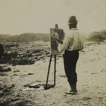 Sepia photo of a man painting at an easel on the beach