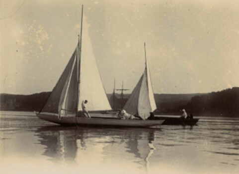 Monochrome photo of two figures in a small sailing boat on the water