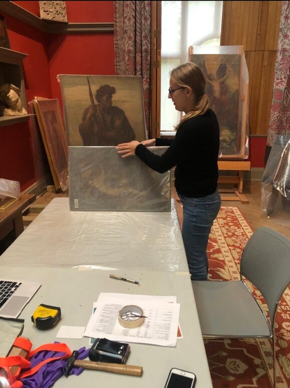A woman unwrapped an oil painting at a table