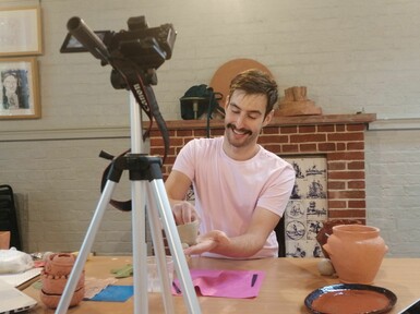 Josh makes something with clay and smiles to the camera