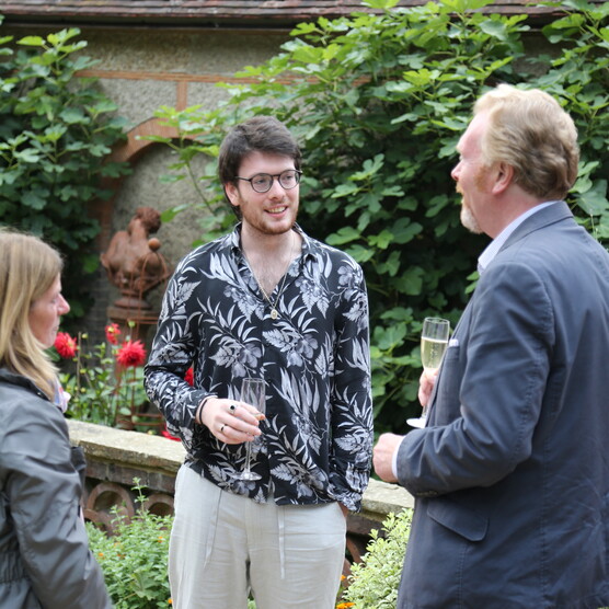 A group of three hold drinks and chat outside the gallery