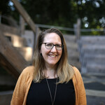 Claire stands in front of our wooden auditorium, she smiles to the camera