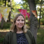 Sarah smiles to camera in woodlands with bunting behind her