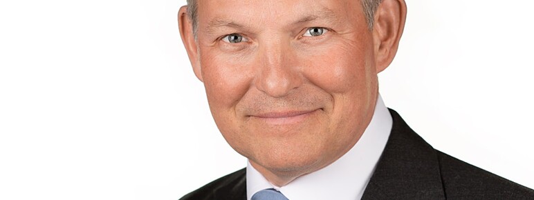 Photo of George Anson, man smiling with greying hair and wearing a suit