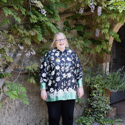 A photo of Sarah King, a lady with short blonde hair wearing glasses and a patterned shirt
