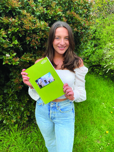 Bryony holds her dissertation and smiles to the camera