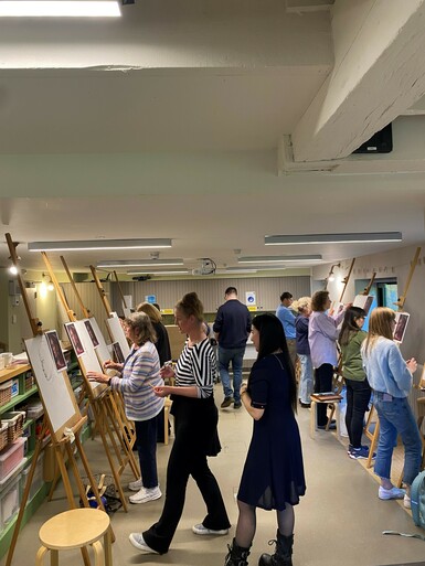 Participants of a portraiture workshops stand drawing at easels