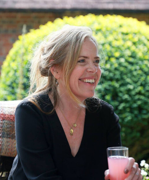 A photograph of Mary Branson smiling, she has long blonde hair that she's wearing down and wearing a black top
