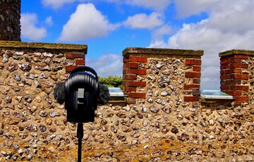 Photo of a microphone on a tripod in front of a stone wall