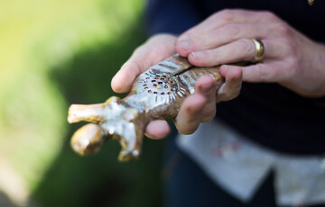 A hand holding a bronze women-figure