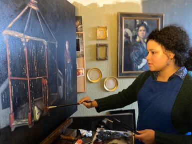 Artist Nneka Uzoigwe paints at an easel in her studio