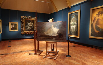 A collection of paintings on easels placed in the centre of the Watts Historic Gallery as part of an intervention