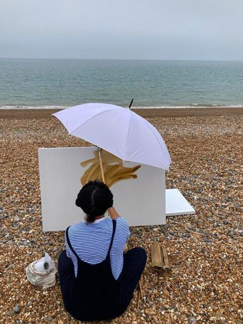 Nneka Uzoigwe painting on the beach as part of her residency