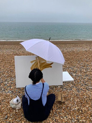 Nneka Uzoigwe painting on the beach as part of her residency