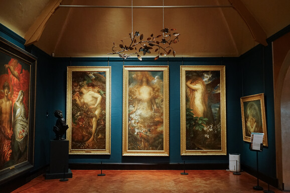 Photo of the inside of Watts Gallery. Suspended from the ceiling is a copper sculpture of flowers and vines
