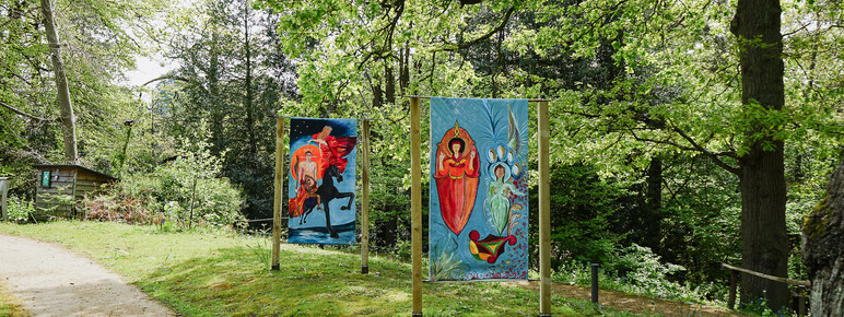 Photo of two paintings on the Limnerslease lawn at Watts Gallery, featuring paintings of some iconic works by George and Mary Watts