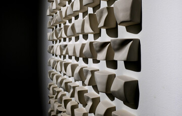 Ceramic sculpture fixed to a wall featuring cubed shapes with different textures.