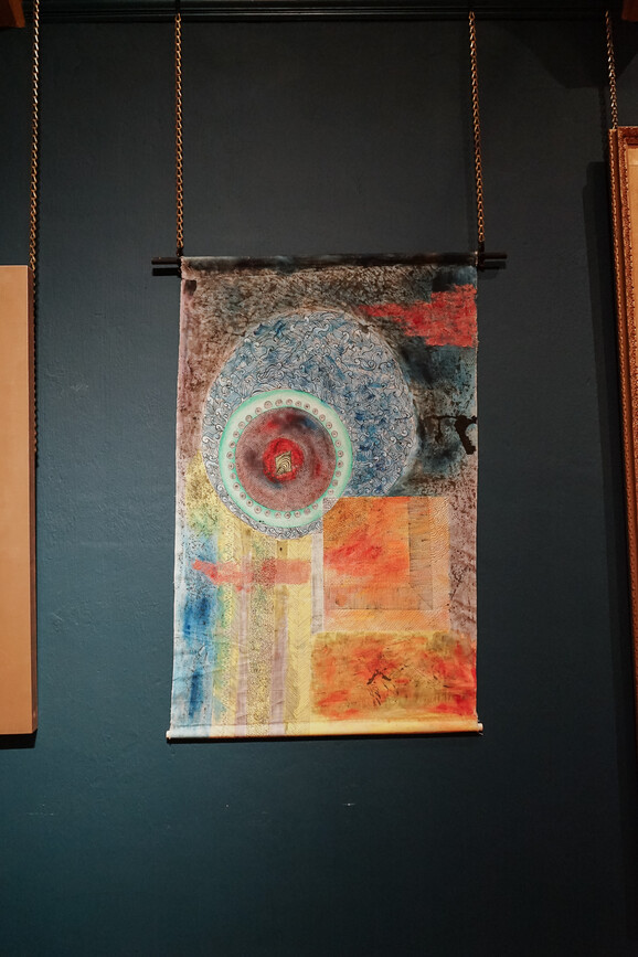 Photo inside the Historic Galleries at Watts Gallery. There is an abstract colourful artwork hung on the wall made from canvas.