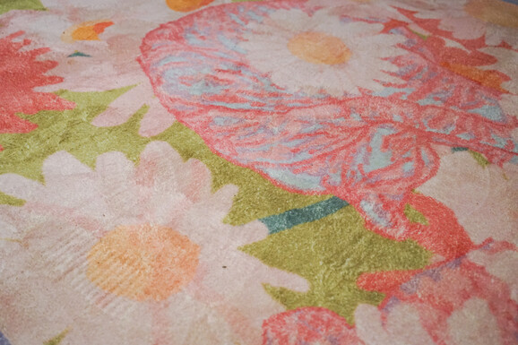 Close up photo of a pink and green rug. The rug is decorated with a floral pattern
