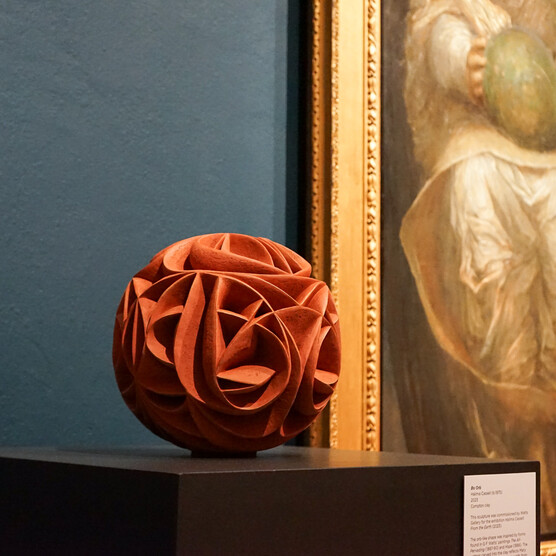 Photo of a spherical terracotta sculpture with curved ridges