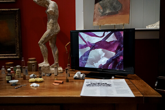 Photo of a monitor screen playing a moving image video with other small objects placed beside it.