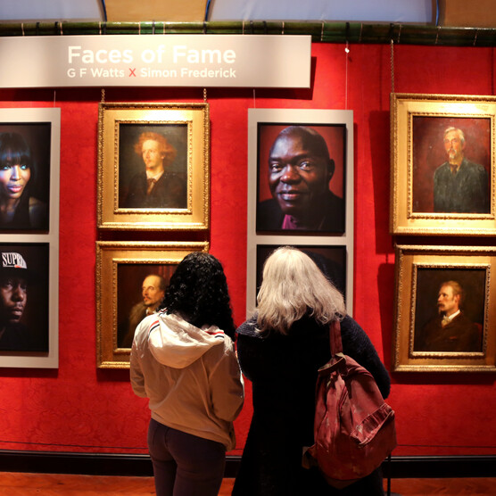 Two visitors look at a portraits hung in the gallery