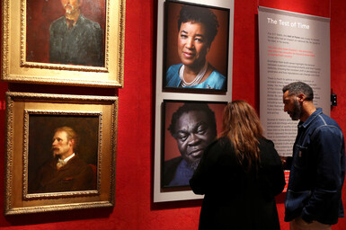 Two visitors look at Faces of Fame exhibition in gallery