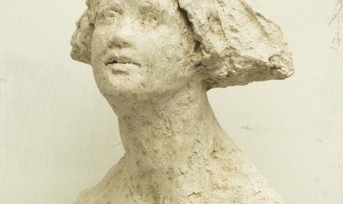 A rough sculpture bust of a woman with a bobbed haircut