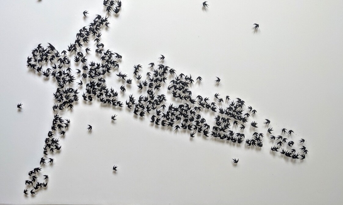 A form of a figure as if in flight created out of small- paper birds on pins