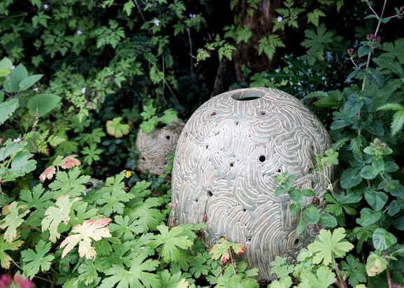 Three ceramic domes of different sizes placed on the ground within vegetation