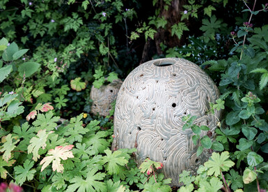 Three ceramic domes of different sizes placed on the ground within vegetation