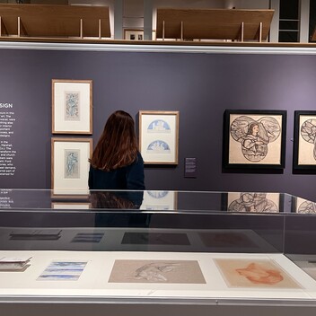 A woman looks towards drawing framed on the wall in the Pre-Raphaelite Treasures exhibition